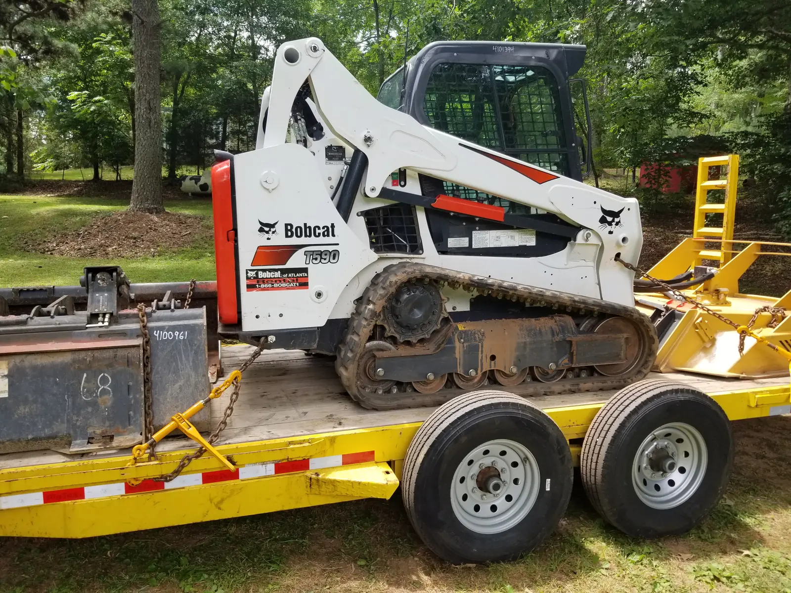 White tracked Bobcat loaded on a yellow equipment trailer